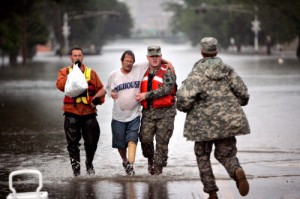 Spc. Scott Wheat runs to the aid of Cedar Rapids Firefighter Brent Smith (left) and Sgt. Brandon Adams (right) as they carry Louie Moran of Cedar Rapids to safety on First Ave W. after being rescued from his home at 814 Third Ave. NE in Cedar Rapids on Thursday evening, June 12, 2008.